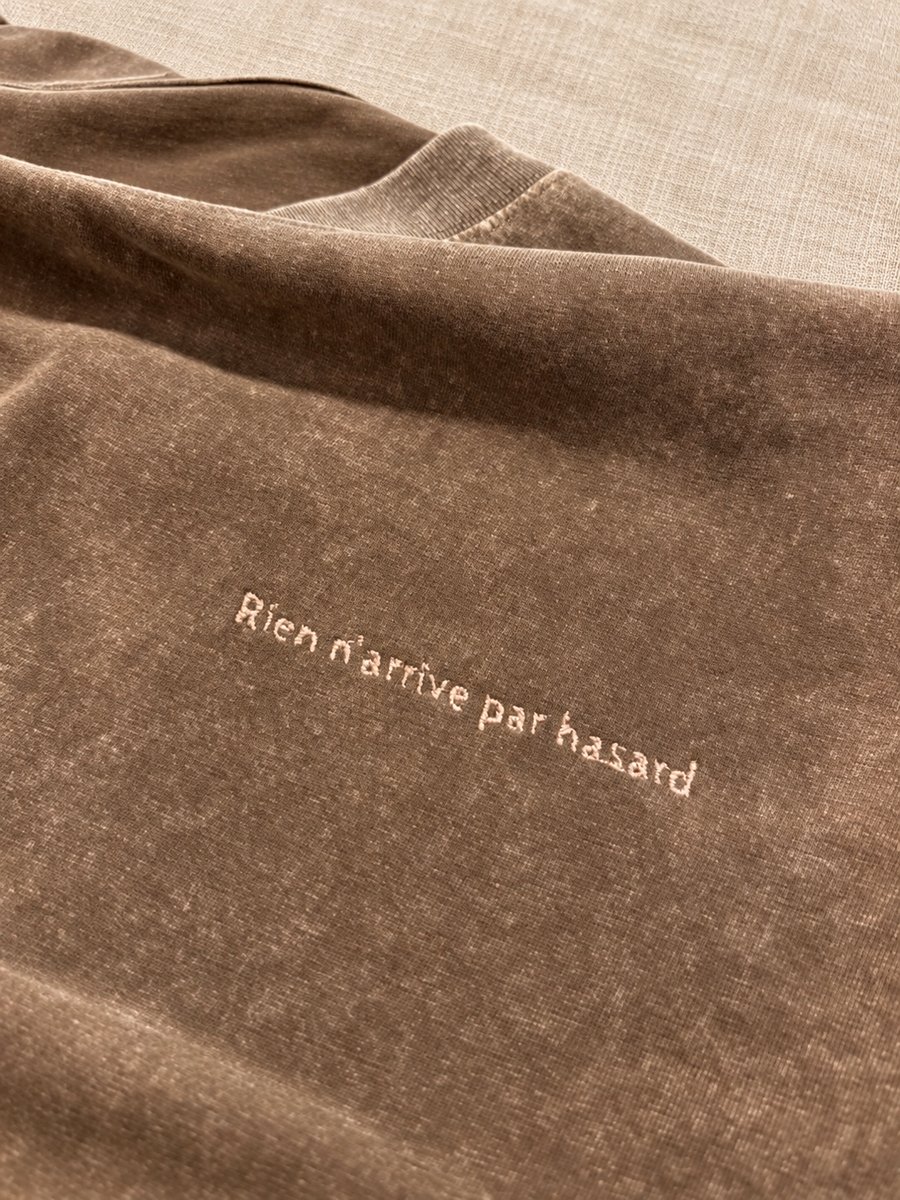 Phrase « Rien n'arrive par hasard » brodée sur un t-shirt en coton délavé